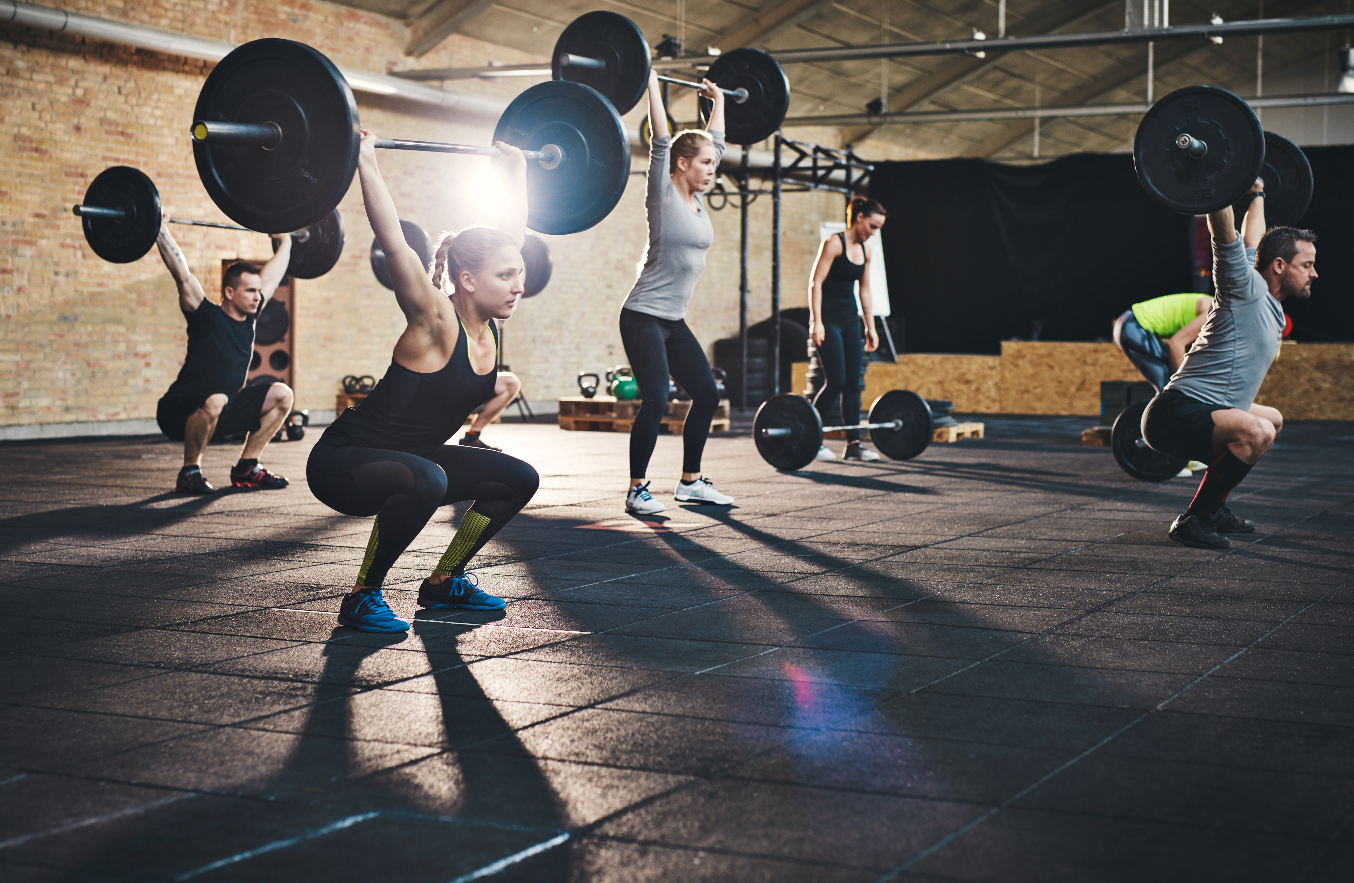 Adults lifting large barbells in fitness class